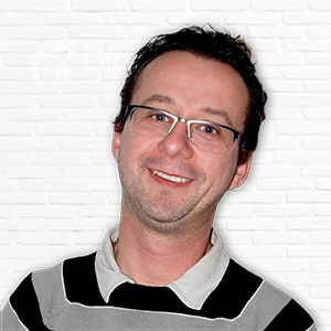 Mann mit Brille vor Ziegelwand