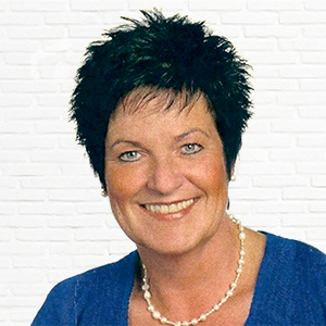 Lächelnde Frau mit blauer Kleidung vor weißer Wand