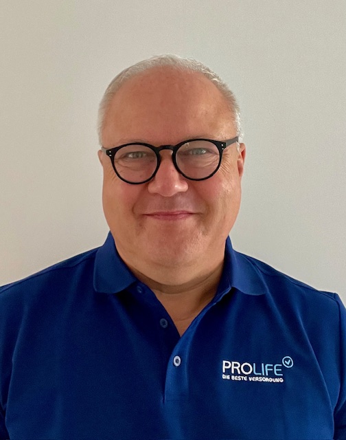 Mann mit Brille in blauem Polohemd vor weißem Hintergrund